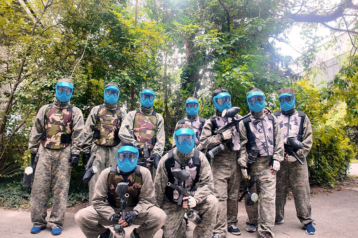 Interns in paintball gear and masks before a game
